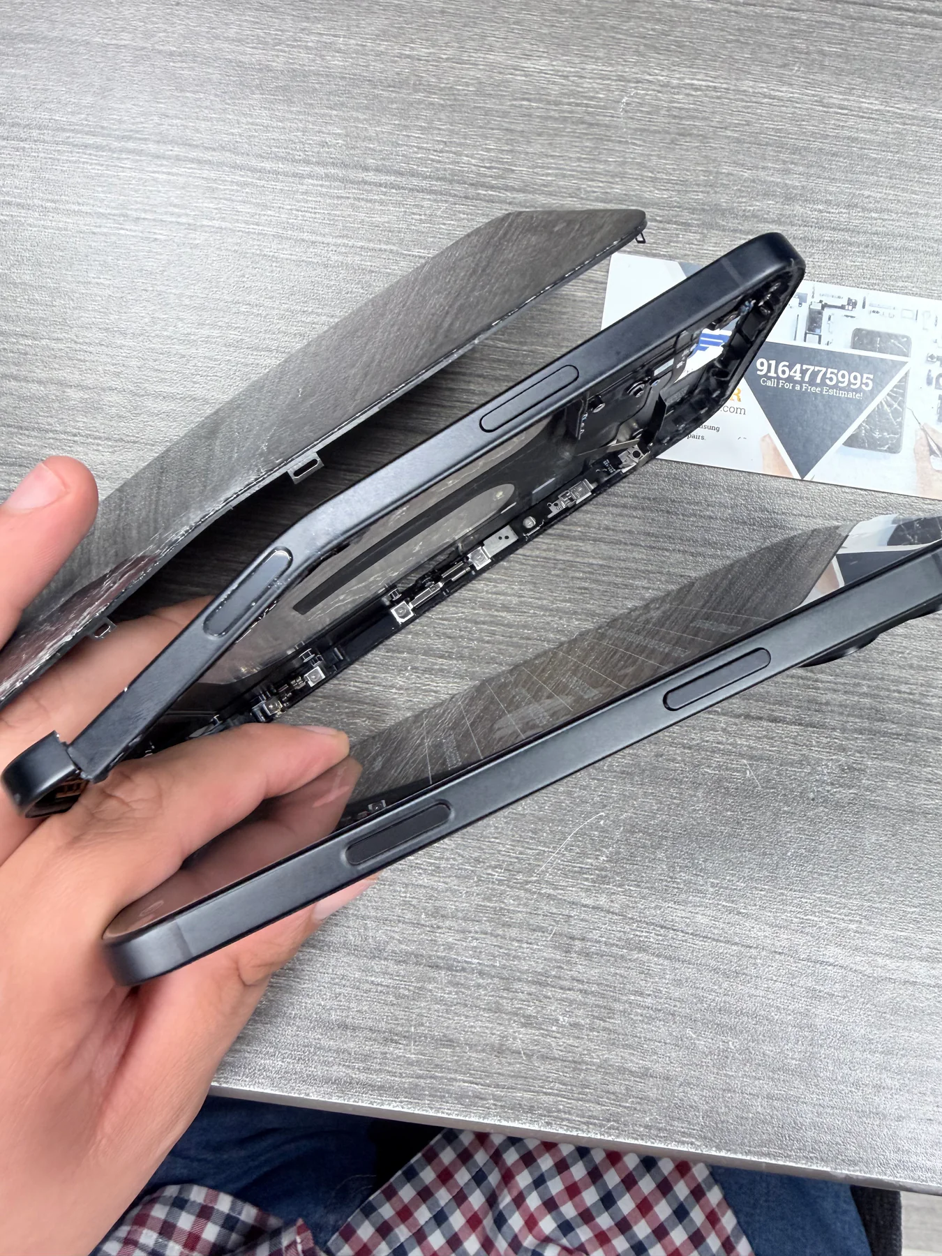 Damaged iPhone 16 Plus housing beside the replacement midframe