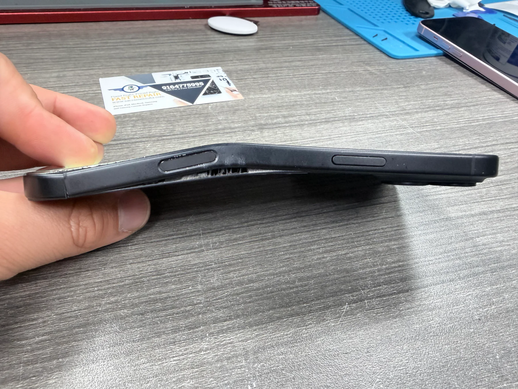 Severely bent iPhone 16 Plus frame after being caught in a car door