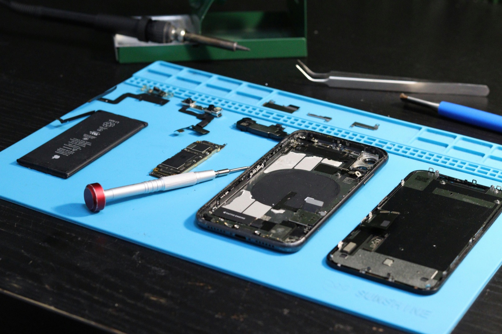 Disassembled smartphone on repair mat during back-glass and housing evaluation
