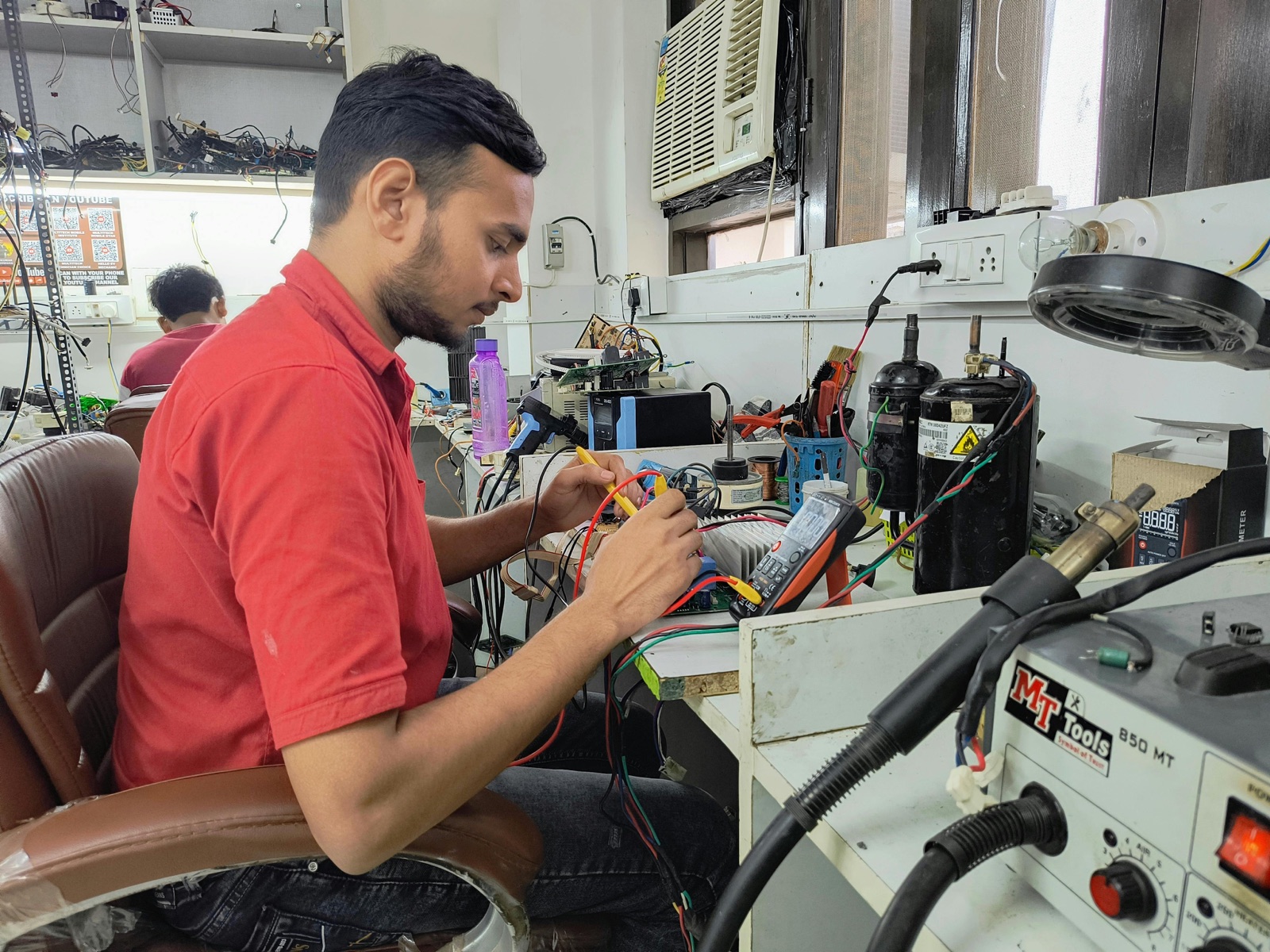 Electronics technician working at a repair bench during overheating diagnosis