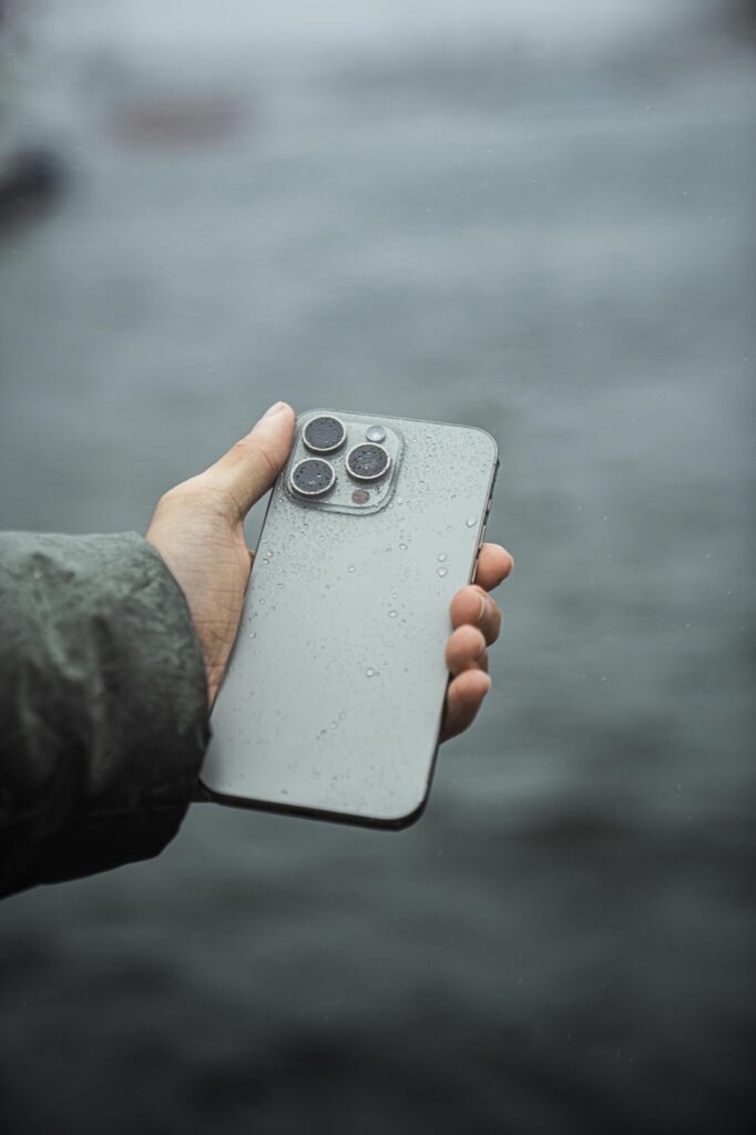 Wet smartphone in hand after rain exposure before water-damage repair