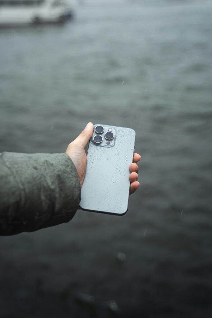 Wet smartphone in hand after rain exposure before water-damage inspection